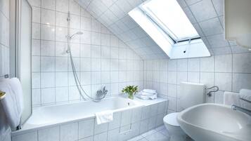 Ein modernes Badezimmer mit Dachfenster, einer Badewanne, einem Waschbecken und einer Toilette.