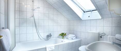 A modern bathroom with a skylight, a bathtub, a sink, and a toilet.