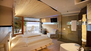 A modern bedroom with a large bed, a small desk, and a shower area. - Ambienthotel Primaluna (Malcesine)