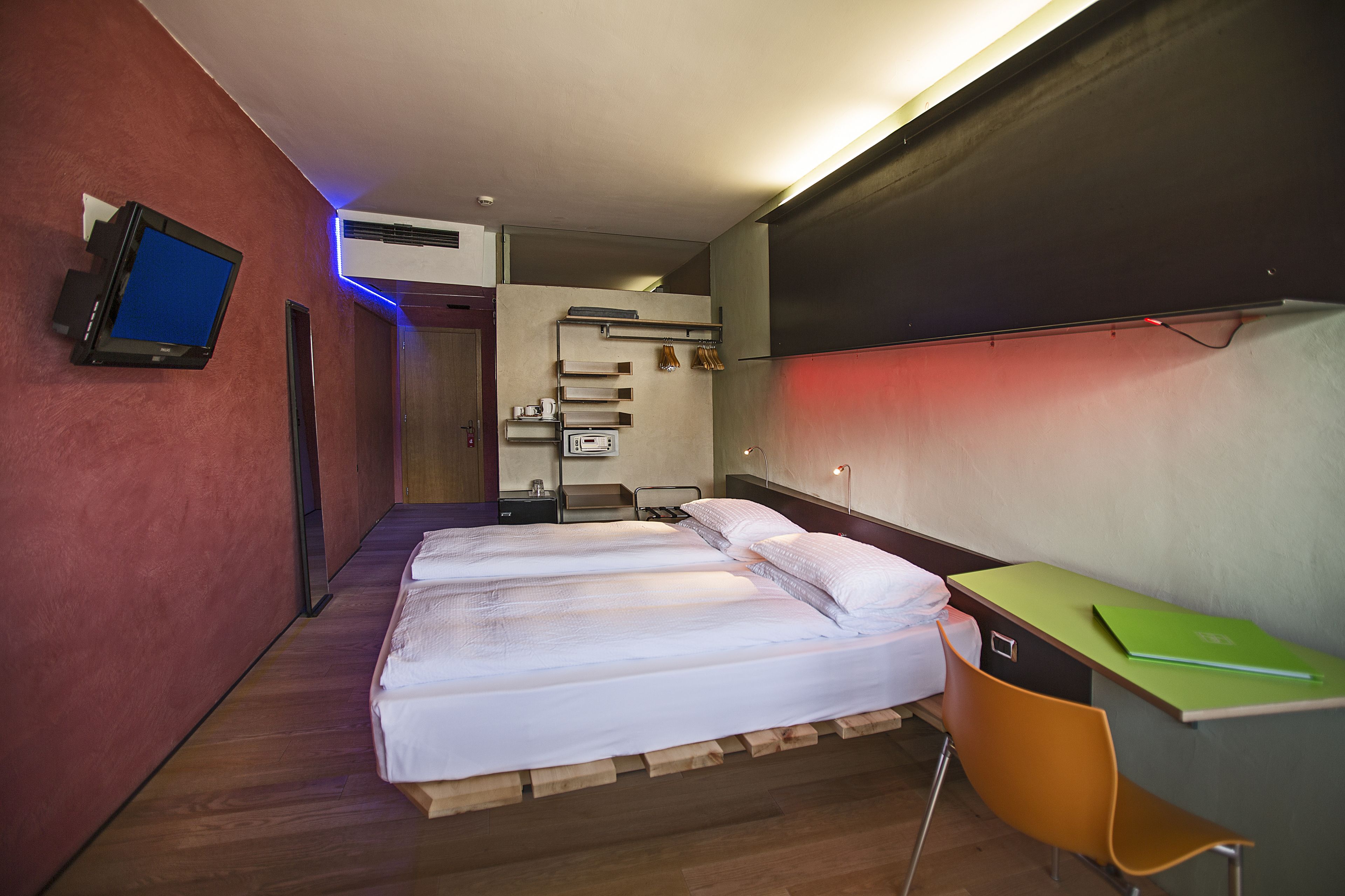 Habitación de hotel con dos camas, un escritorio, un televisor y un baño visible a través de una puerta abierta.