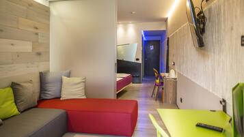 Una habitación de hotel moderna con un sofá rojo, una mesa verde y una cama con colchón rojo.