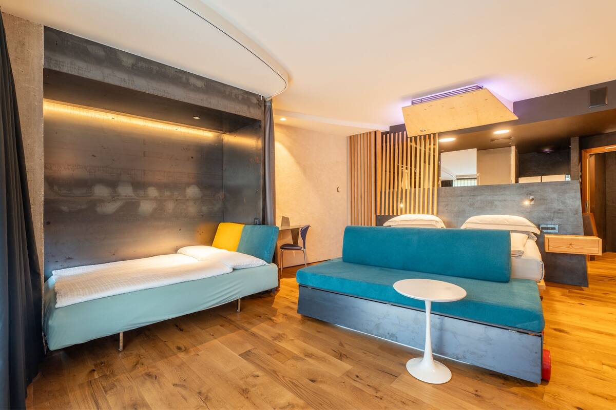 A modern hotel room with a bed, a sofa, and a small table.