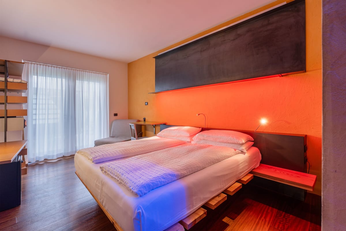 A modern bedroom with a large bed, a desk, and a chair.