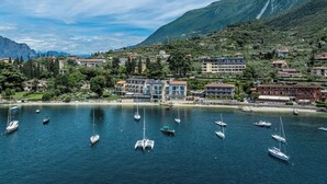 Un pueblo costero con edificios, un puerto deportivo y montañas al fondo.