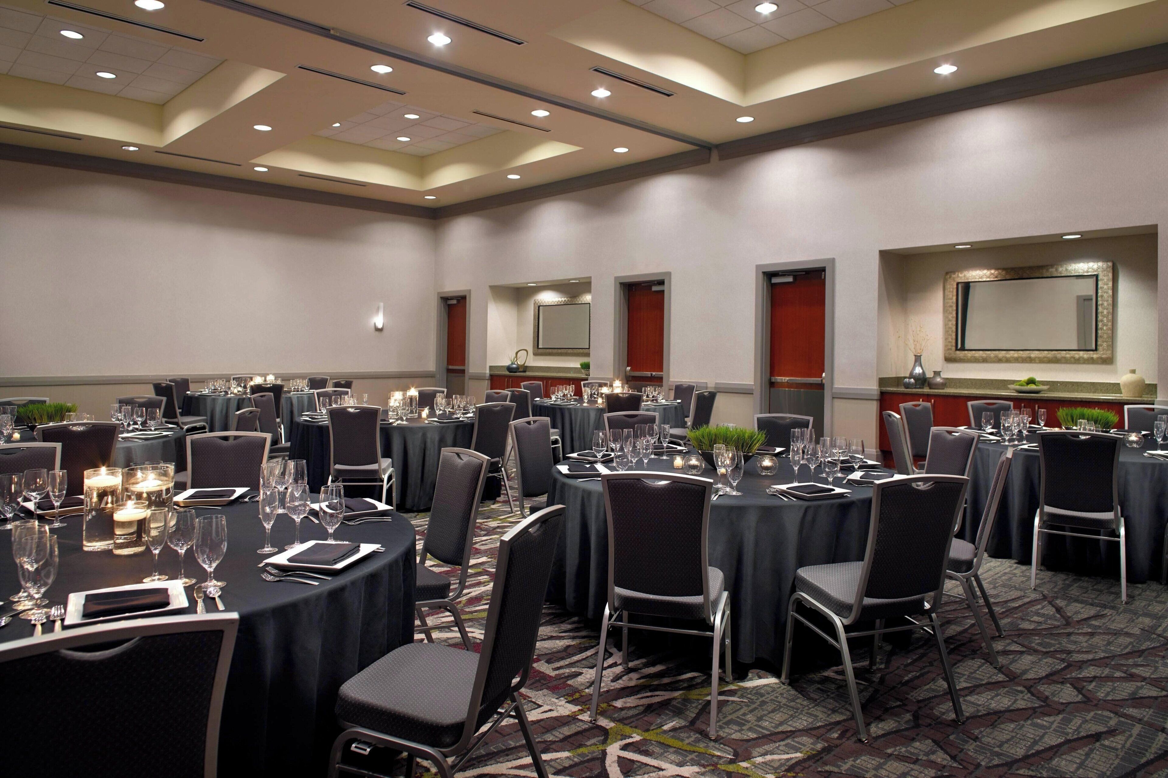 A conference room with round tables, chairs, and a carpeted floor.