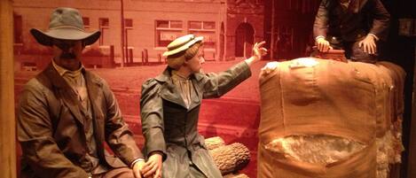 A display with mannequins in period clothing, a large sack, and a building facade in the background.