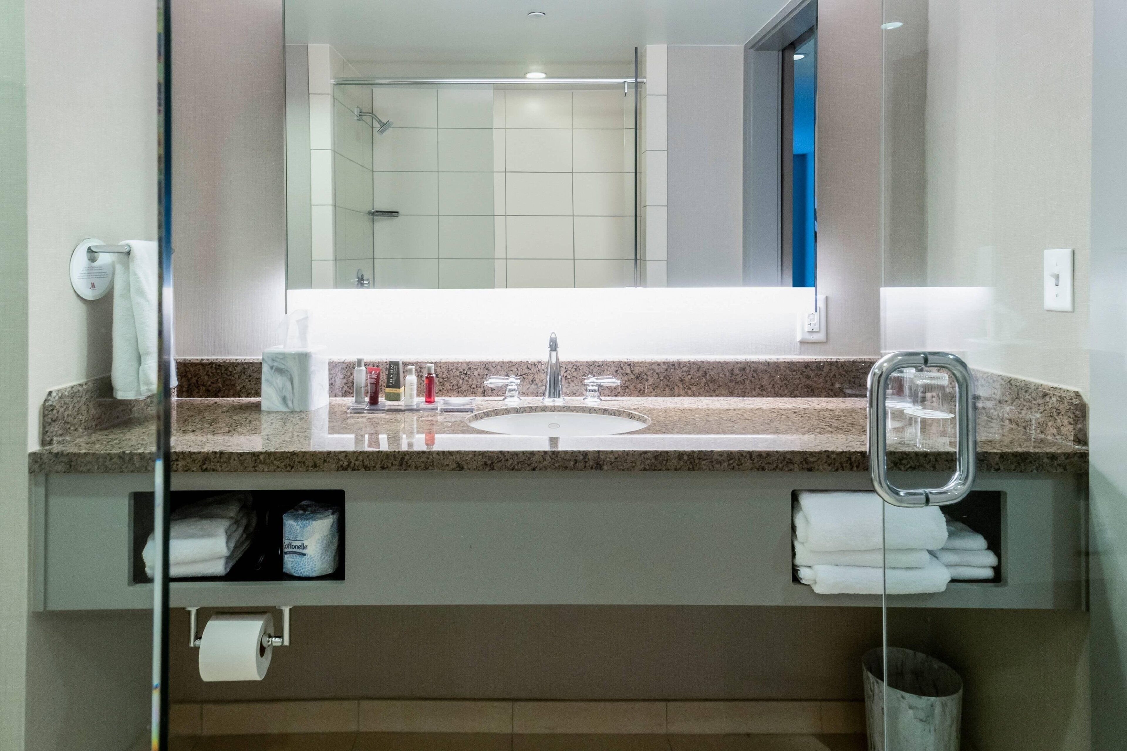 Une salle de bain moderne avec un comptoir en granit, un lavabo et un miroir.