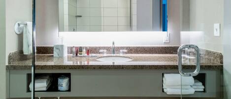 Une salle de bain moderne avec un comptoir en granit, un lavabo et un miroir.