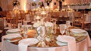 A banquet hall with round tables set for a formal event, featuring white tablecloths, gold cutlery, and floral centerpieces. - Raleigh Marriott City Center (Raleigh)