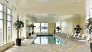 An indoor swimming pool with lounge chairs and potted plants.