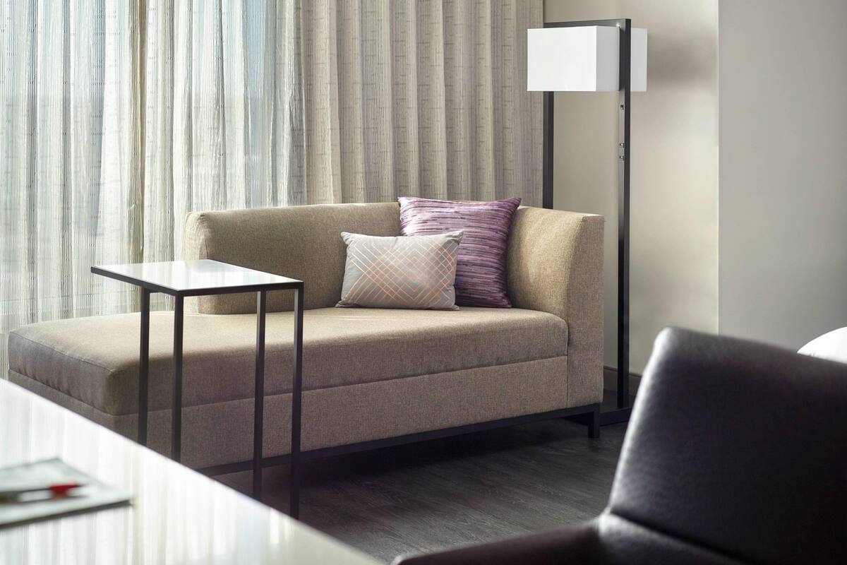 A modern hotel room with a sofa, a small table, and a floor lamp.