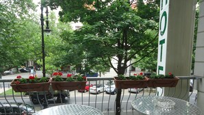 A balcony with two metal tables and flower planters. - City Hotel am Kurfürstendamm (Berlin)