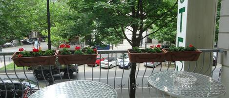 A balcony with two metal tables and flower planters.
