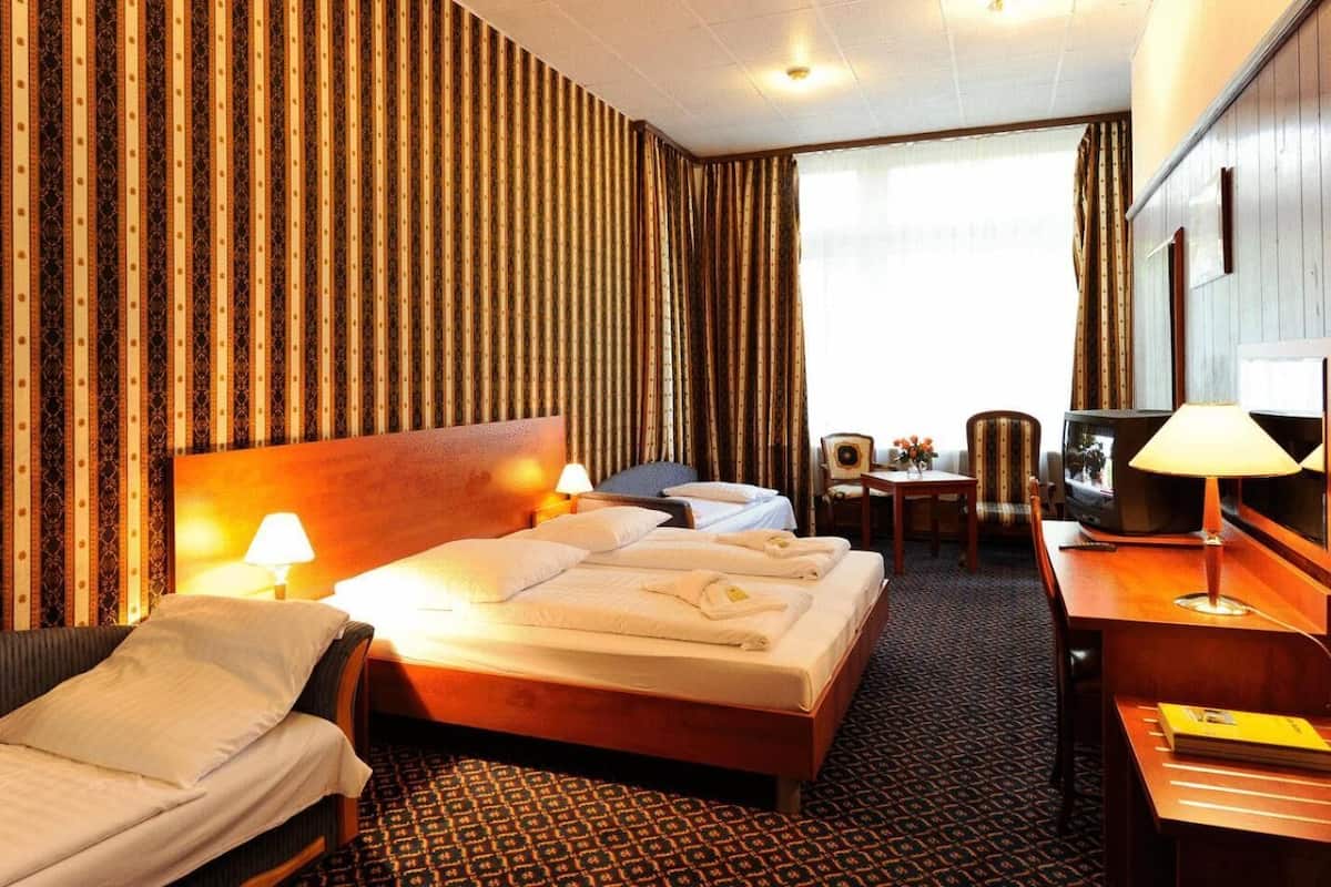 Une chambre d’hôtel avec un grand lit, un bureau avec une lampe, une télévision et une chaise.