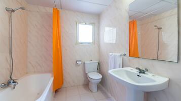A bathroom with a bathtub, toilet, and sink.