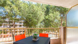 A balcony with a table and chairs, overlooking a building and trees. - Rentalmar Salou Pacific (Salou)