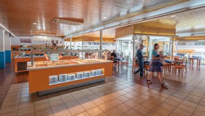 A buffet area with a central serving station, multiple seating arrangements, and a high ceiling with wooden panels. - Rentalmar Salou Pacific (Salou)