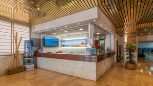 A reception area with a marble counter, a digital screen, and a wooden ceiling. - Rentalmar Salou Pacific (Salou)