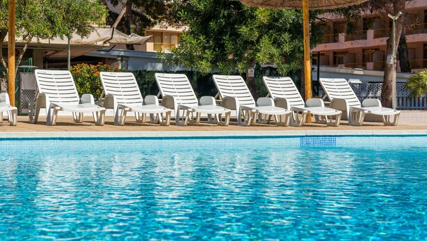 A poolside area with lounge chairs and a clear blue pool. - Rentalmar Salou Pacific (Salou)