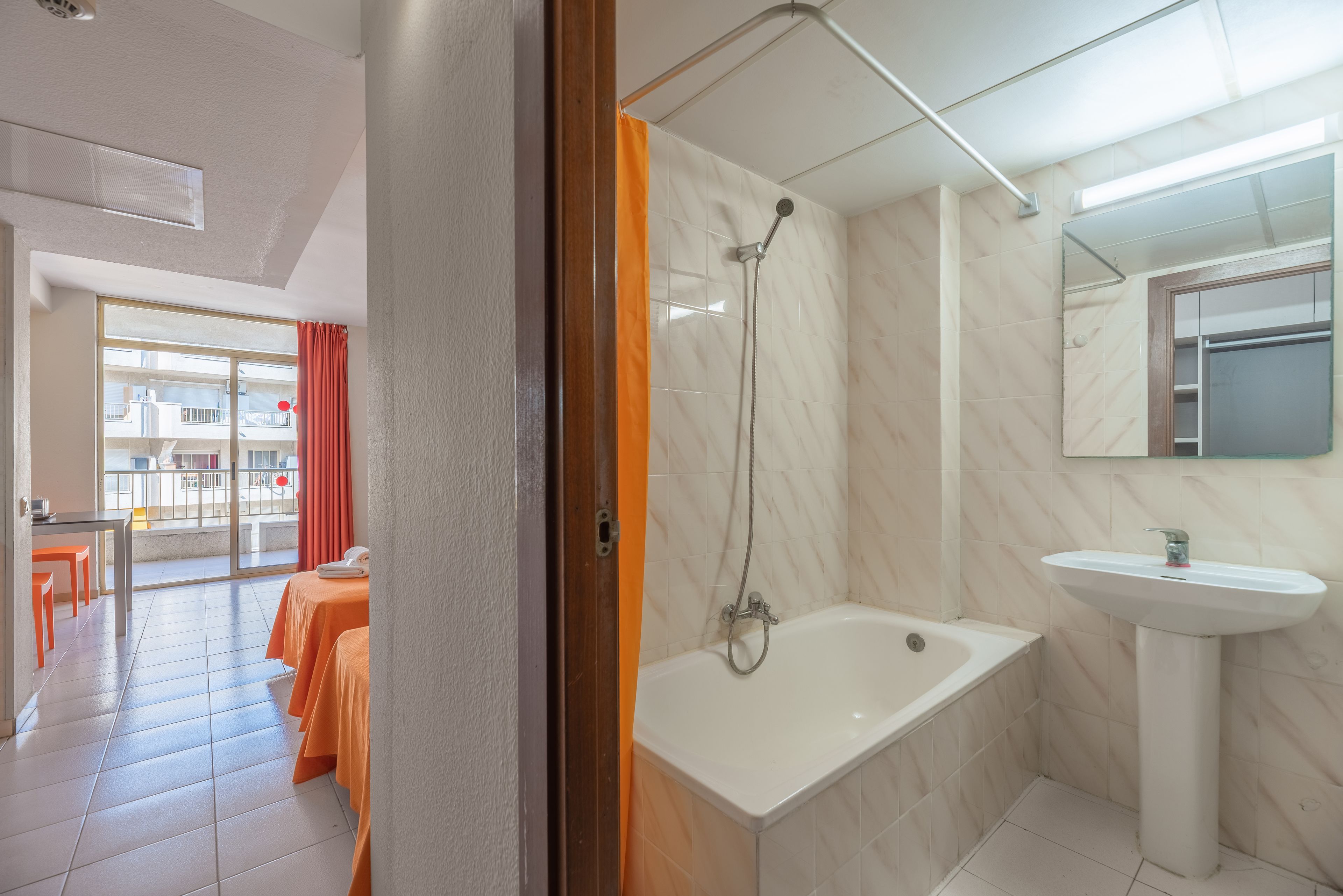 Habitación de hotel con baño que incluye una bañera, un lavamanos y una ducha.