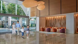 A modern lobby with a glass entrance, a seating area with colorful cushions, and pendant lighting.