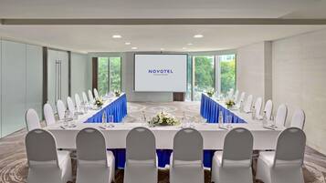 A conference room with a long table, white chairs, and a screen displaying 'NOVOTEL SAIGON CENTRE'.