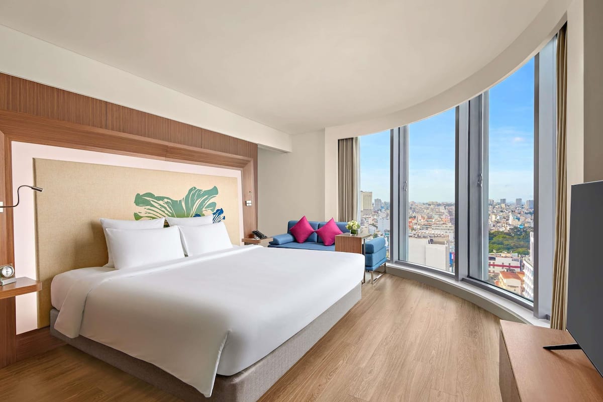 Een moderne hotelkamer met een groot bed, een bureau en uitzicht op de stad.