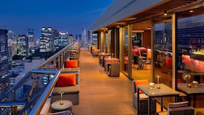 A rooftop bar with outdoor seating and a city view.