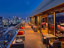 Un bar en la azotea con mesas al aire libre y vistas de la ciudad.