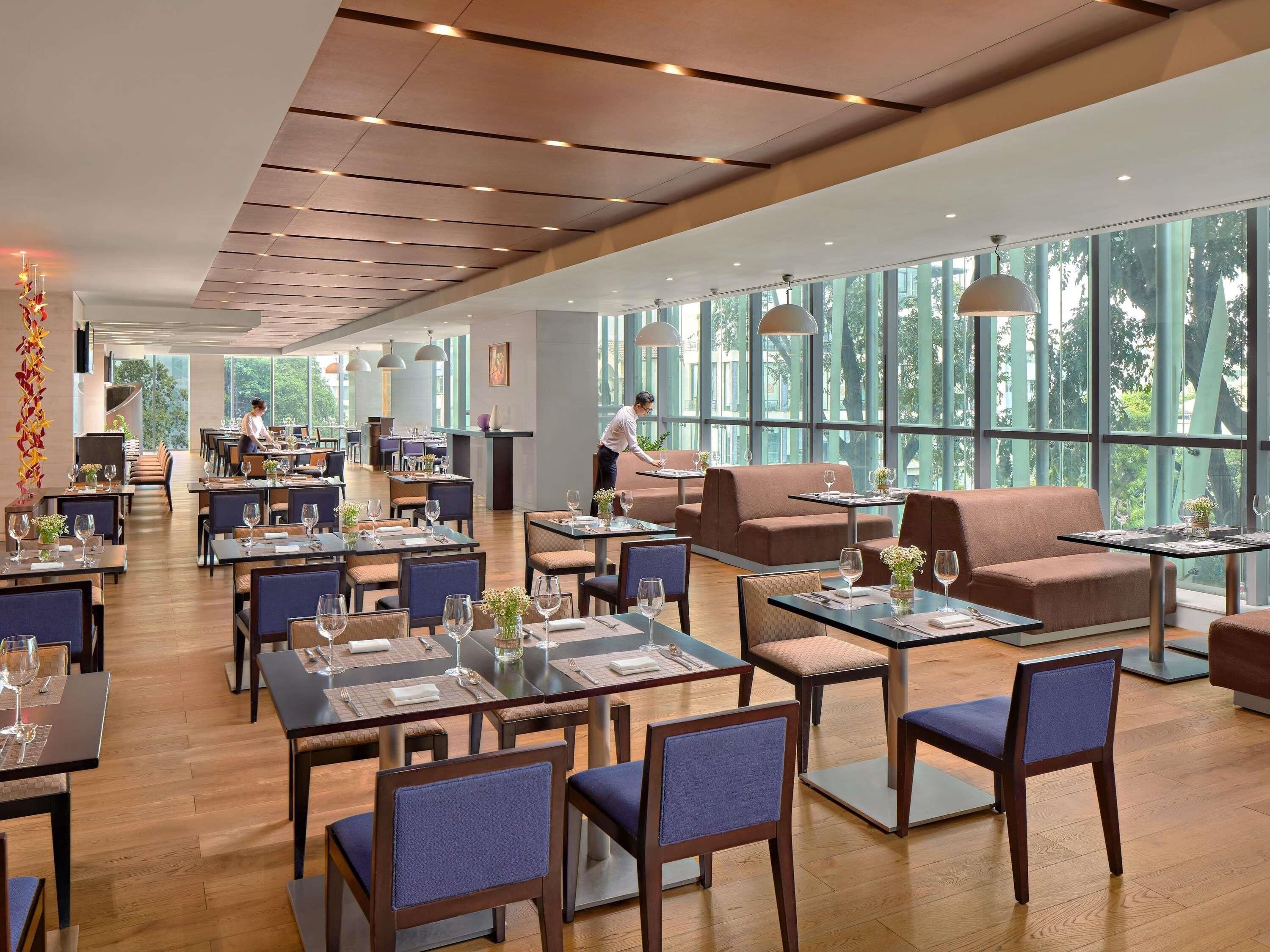 A spacious restaurant with high ceilings, large windows, and modern furniture.