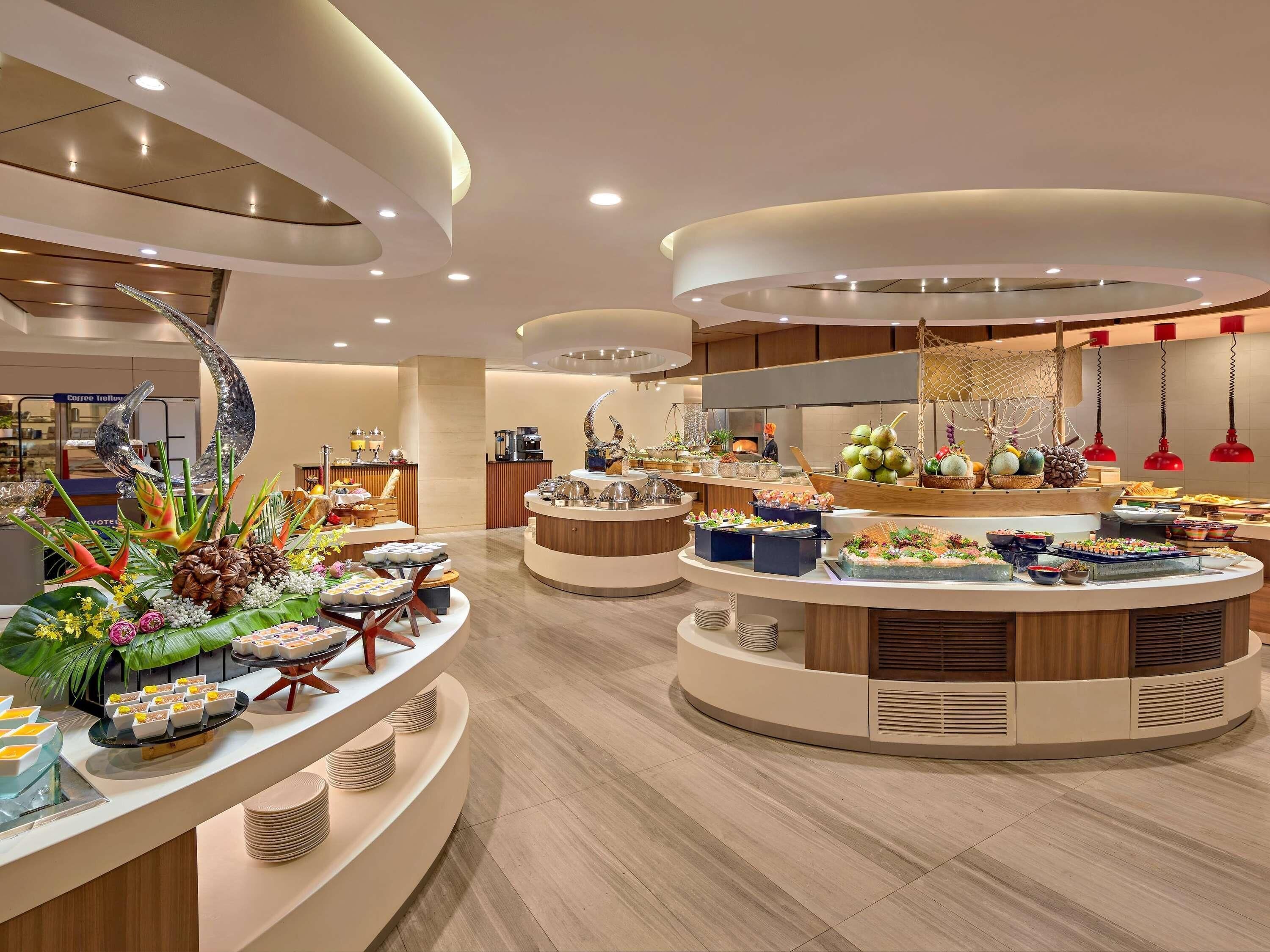 A modern buffet setup with multiple serving stations, including a variety of food items and decorative elements.