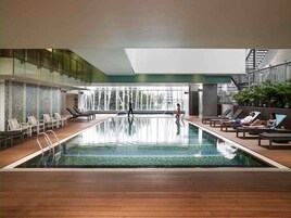 Una piscina interior con sillones de descanso y vistas al exterior.