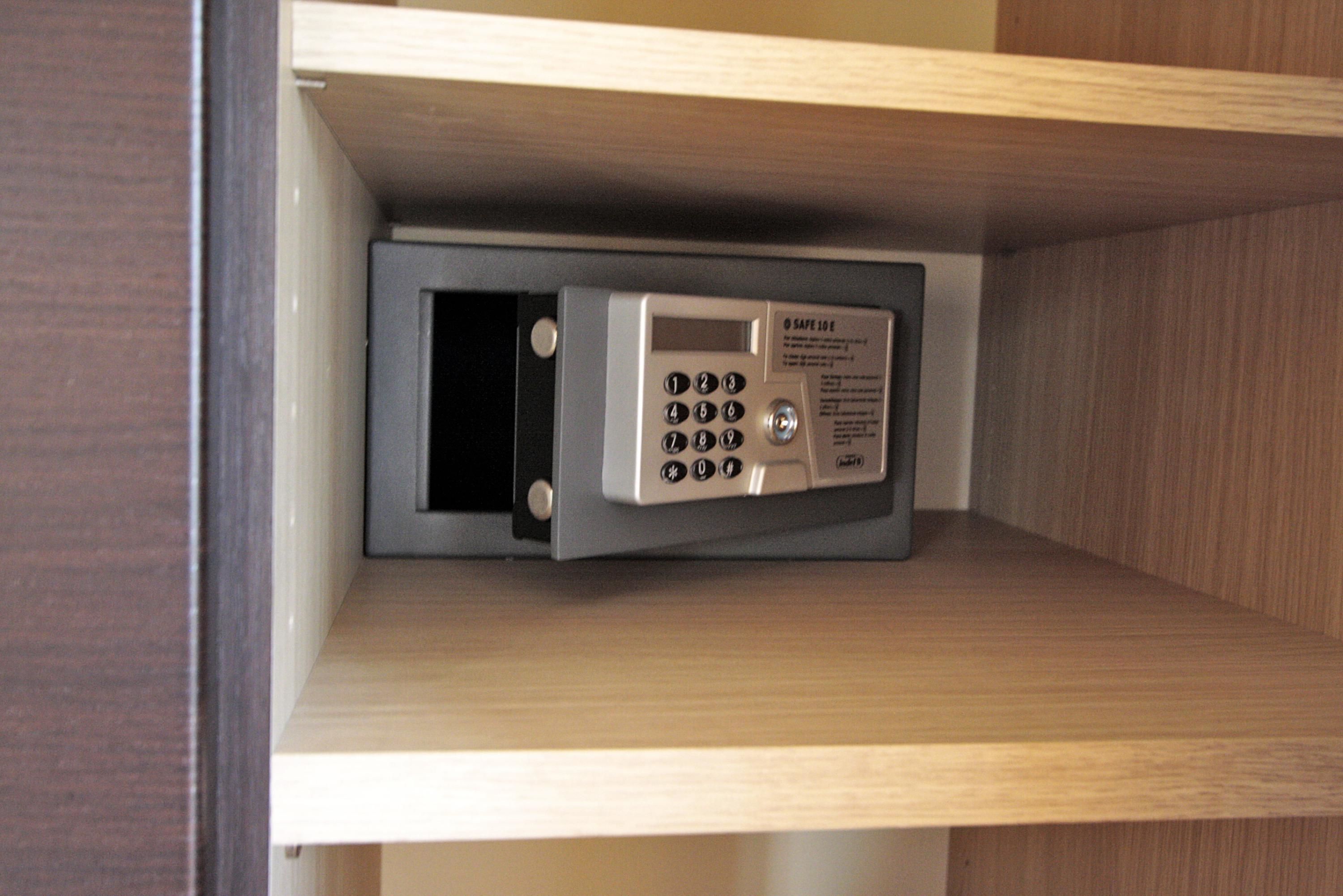 Una caja fuerte con teclado y mecanismo de bloqueo, instalada dentro de un armario de madera.