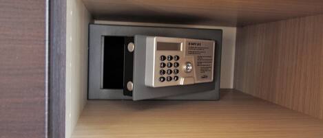 Una caja fuerte con teclado y mecanismo de bloqueo, instalada dentro de un armario de madera.
