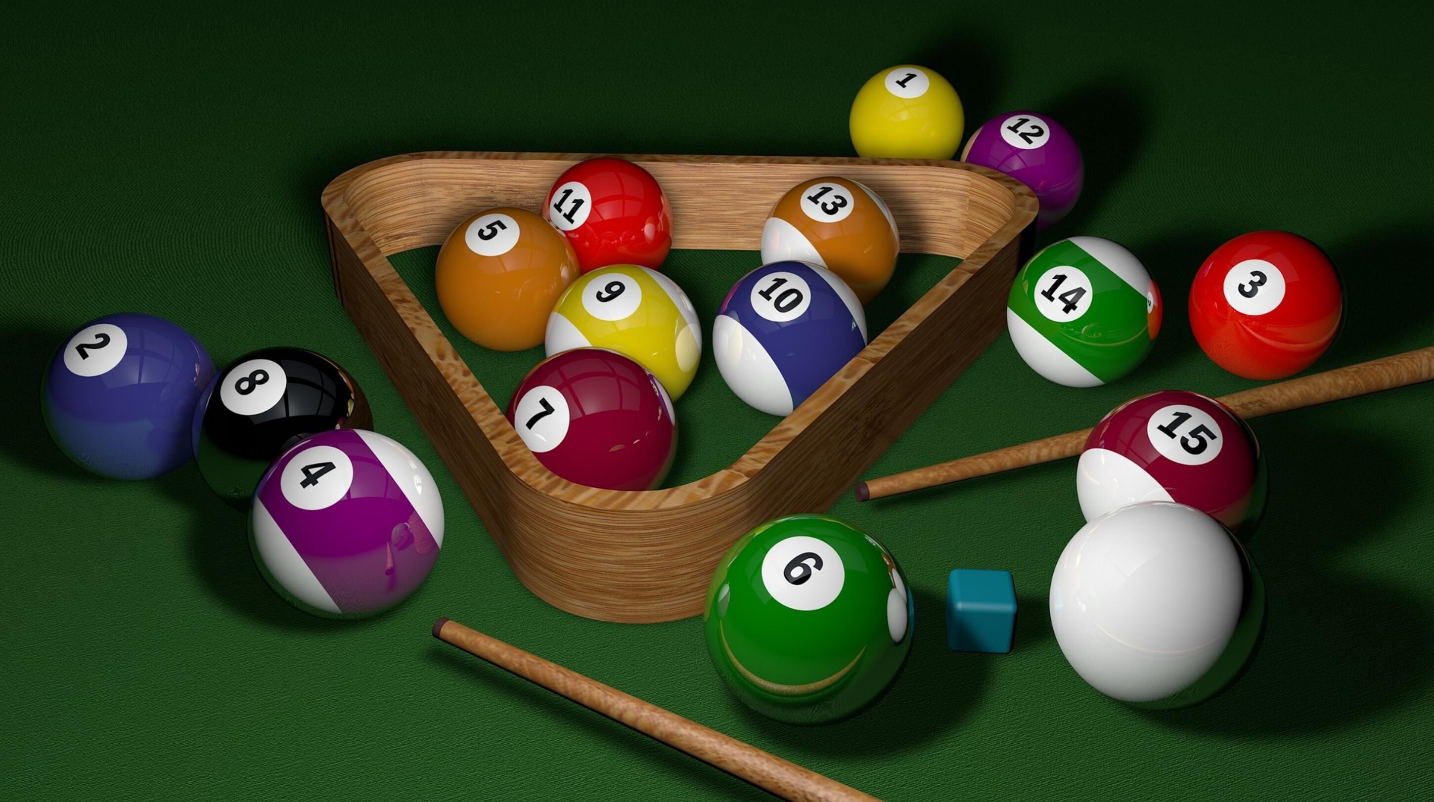 A pool table with a wooden frame, billiard balls, and cues.