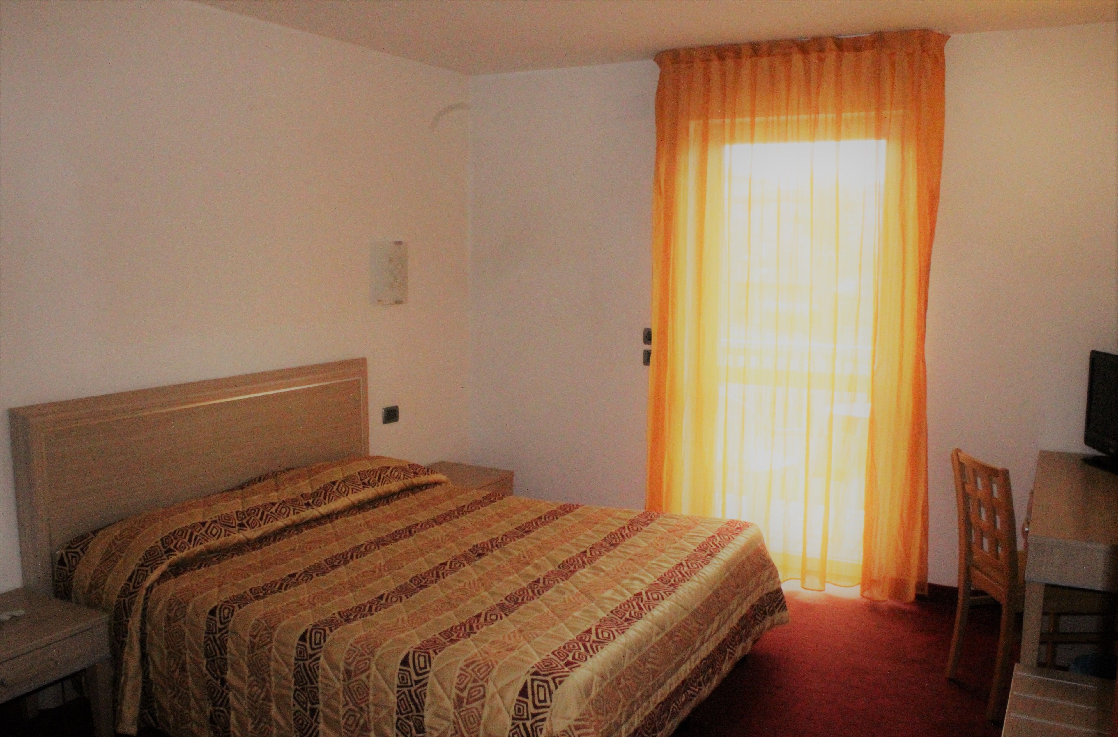 A hotel room with a bed, a desk, and a chair.