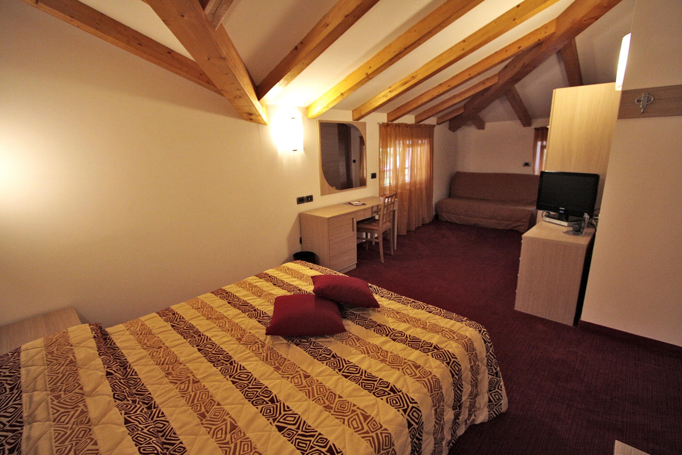 Un dormitorio con cama, escritorio, silla y televisor.
