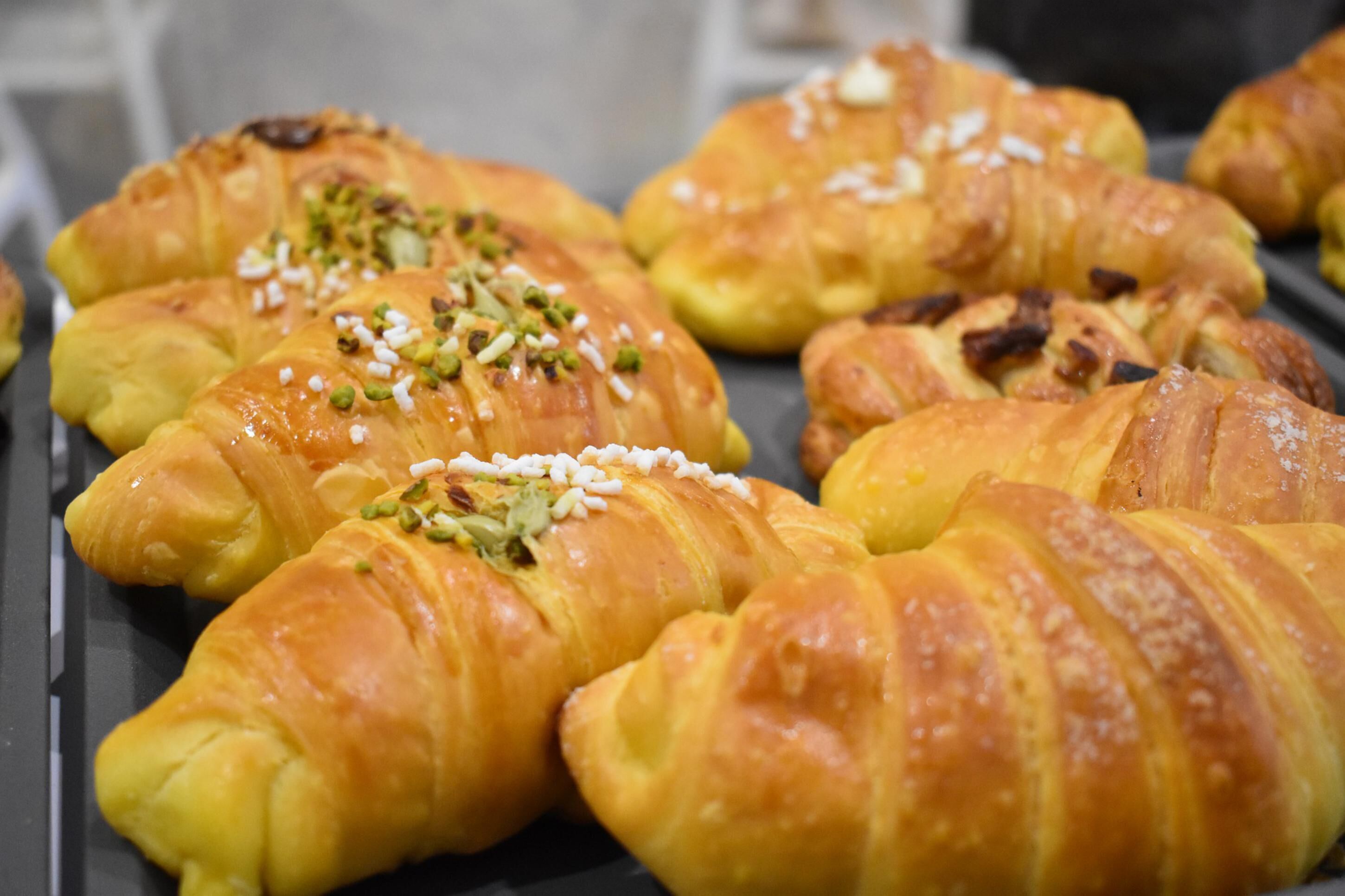 Una bandeja con varios pasteles, incluyendo croissants y un pastelito cubierto de nueces y azúcar.
