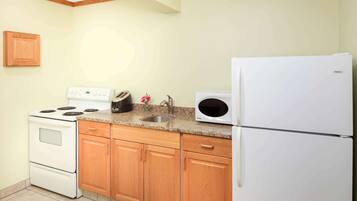 A kitchen with wooden cabinets, a white stove, a microwave, and a refrigerator.
