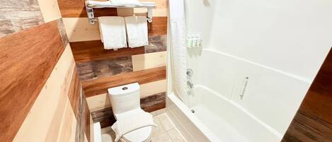 Une salle de bain équipée de toilettes, d’une douche et d’un porte-serviettes.
