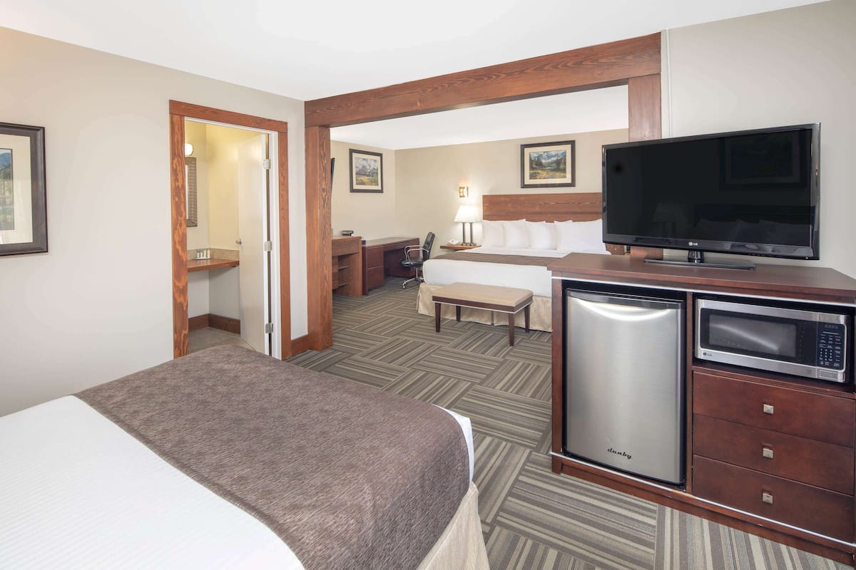 A hotel room with a bed, a desk, a television, and a microwave.