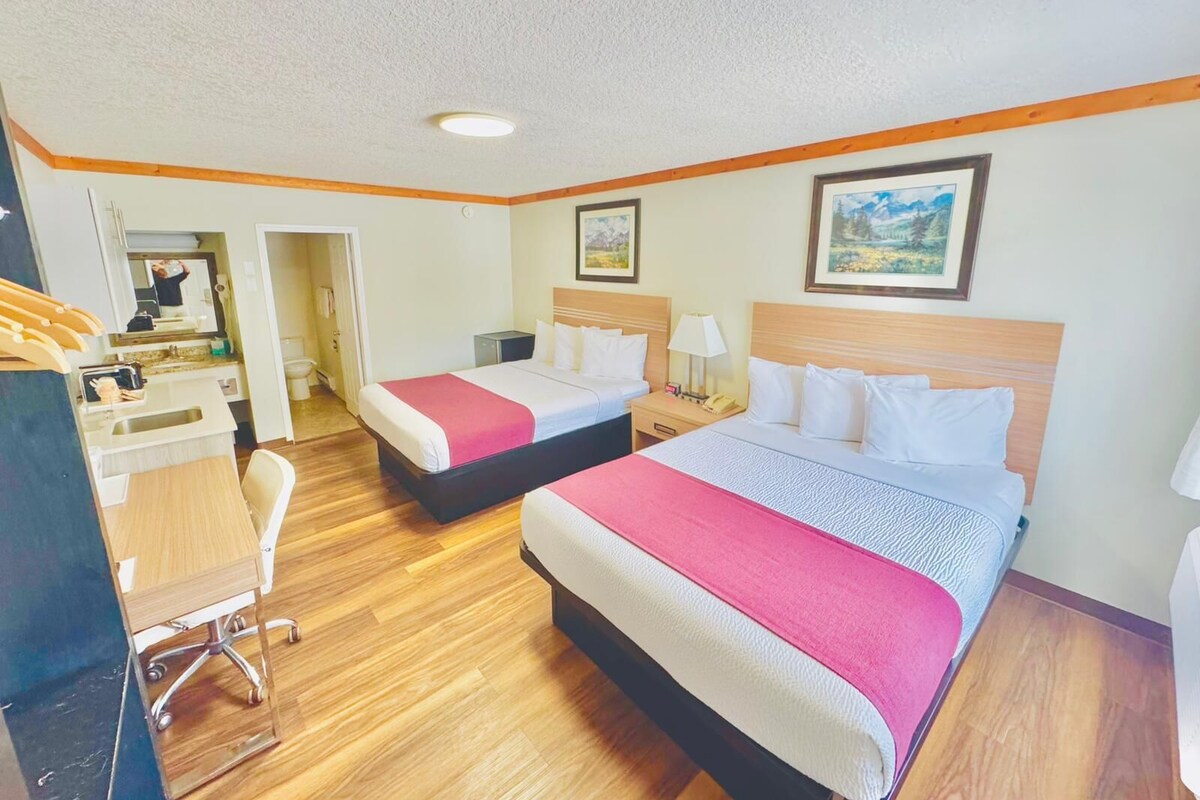 A hotel room with two beds, a desk, and a chair.