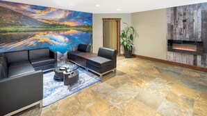 A modern lobby with a large mural, a fireplace, and comfortable seating. - Travelodge by Wyndham Golden Sportsman Lodge (Golden)