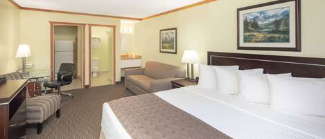A hotel room with a large bed, a desk with a chair, a sofa, and a small table with a lamp.