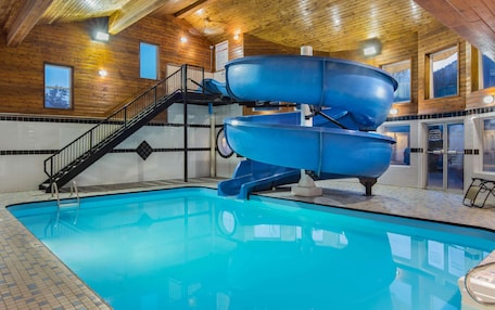 A swimming pool with a blue water slide and a staircase leading to the slide.