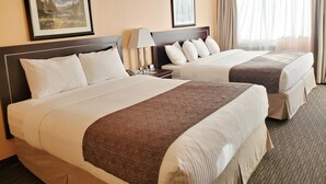Two double beds with headboards, bedside tables with lamps, and framed artwork on the walls. - Travelodge by Wyndham Golden Sportsman Lodge (Golden)