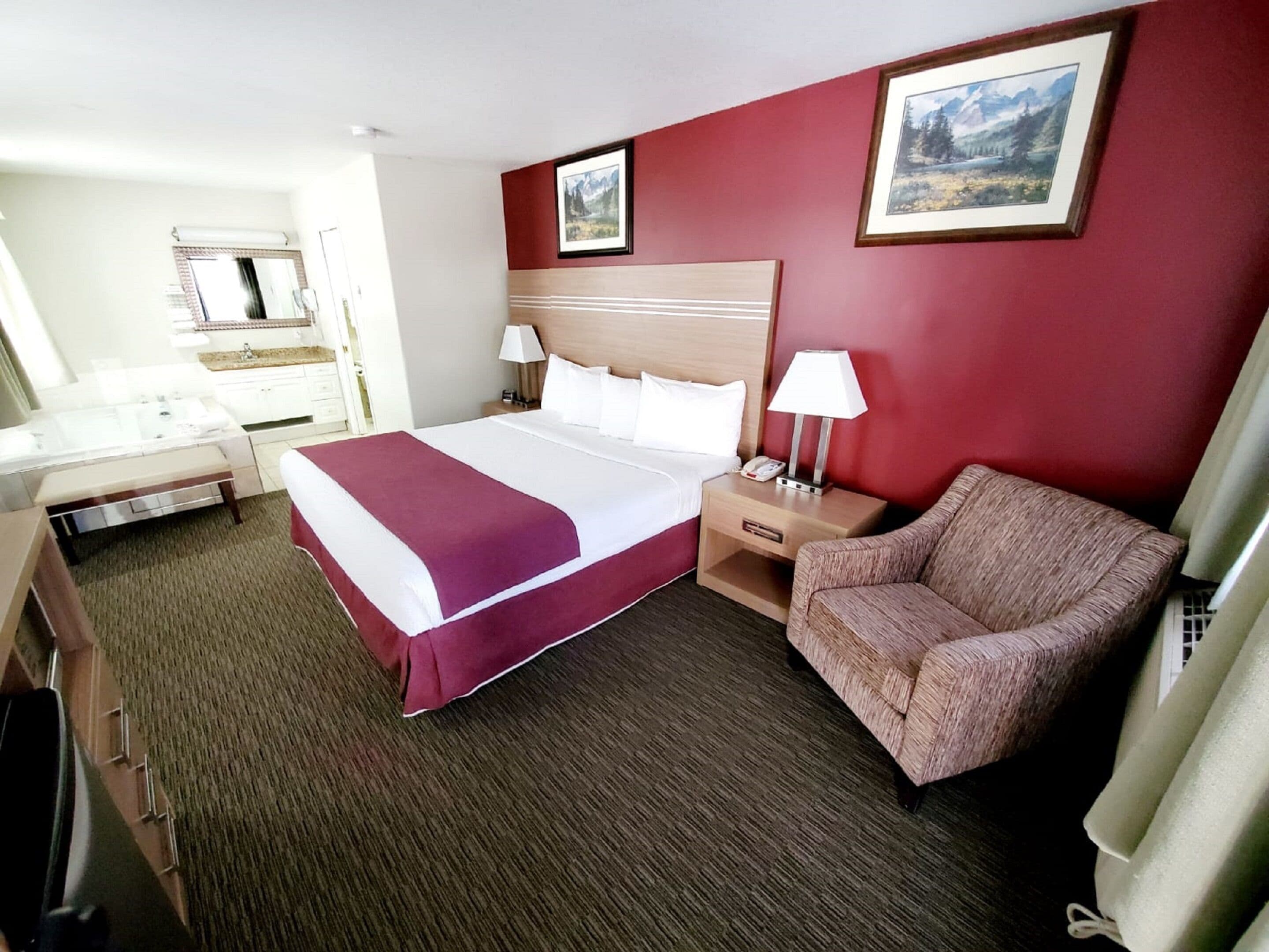Une chambre d’hôtel avec un grand lit, un bureau, une chaise et deux tableaux au mur.