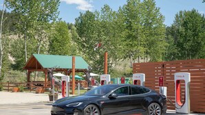 A Tesla electric car charging at a station with a wooden structure and trees in the background. - Travelodge by Wyndham Golden Sportsman Lodge (Golden)