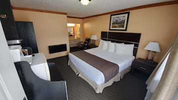A hotel room with a bed, a desk, a chair, a nightstand, a lamp, and a painting on the wall.