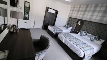 A hotel room with two beds, a desk, a chair, a mirror, and a television.